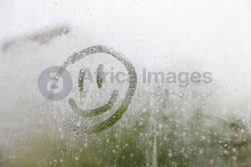 Funny face drawn on foggy window, space for text. Rainy weather