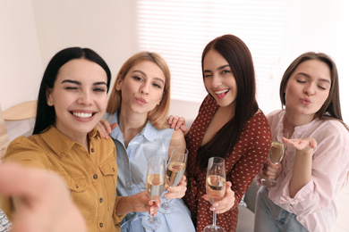 Beautiful young ladies with champagne taking selfie at home. Women's Day