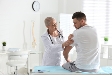 Male orthopedist examining patient's arm in clinic