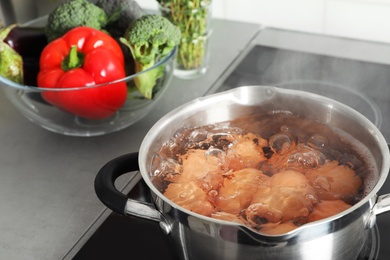 Cooking chicken eggs in pot on electric stove at kitchen