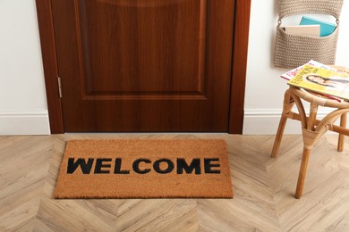 Door mat with word Welcome on wooden floor in hall