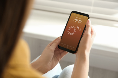 Image of Woman using weather forecast app on smartphone indoors, closeup