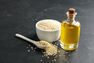 Bottle of sesame oil and seeds on black table