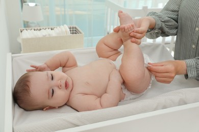 Photo of Mother changing baby's diaper on table at home
