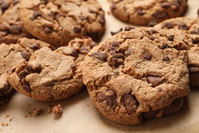 Photo of Delicious chocolate chip cookies on parchment paper, closeup