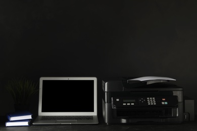 New modern printer, laptop and office supplies on black table