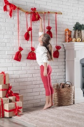 Photo of Little girl taking gift from New Year advent calendar at home