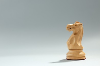 Wooden knight on light background, space for text. Chess piece