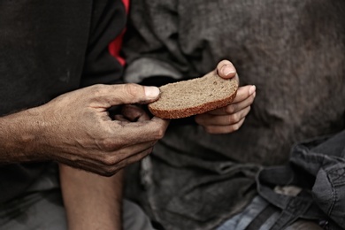 Poor homeless people sharing piece of bread outdoors, closeup