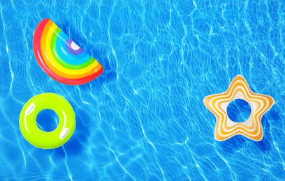 Different inflatable rings floating in swimming pool, top view