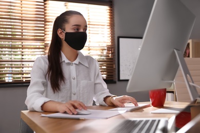 Female worker with mask in office. Protective measure during COVID-19 pandemic