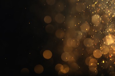 Blurred view of golden lights on black background. Bokeh effect