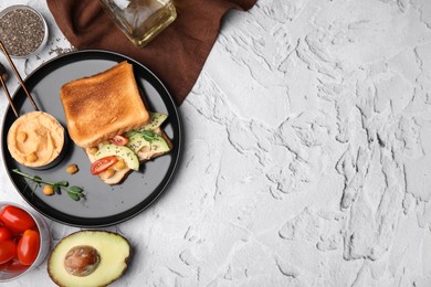 Delicious sandwich with hummus and vegetables, ingredients on white textured table, flat lay