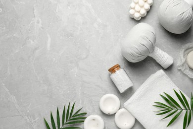 Flat lay composition with herbal massage bags and other spa products on grey marble table, space for text