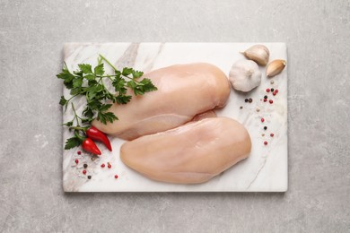Raw chicken breasts and ingredients on light grey table, top view