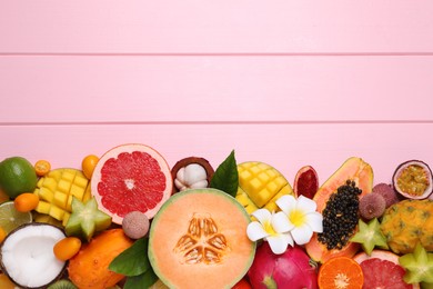 Different exotic fruits on light pink wooden background, flat lay. Space for text