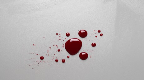 Drops of blood on grey background, top view