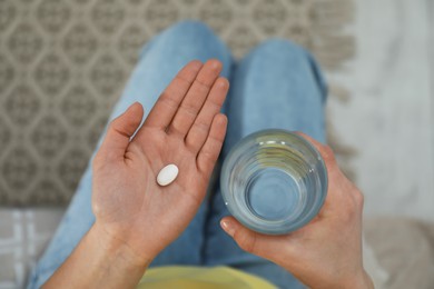 Young woman with abortion pill and glass of water, top view