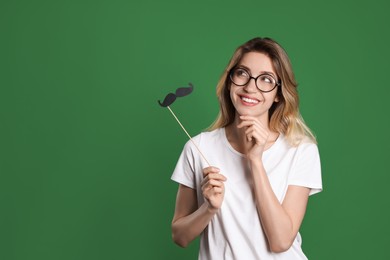 Photo of Funny woman with fake mustache on green background, space for text