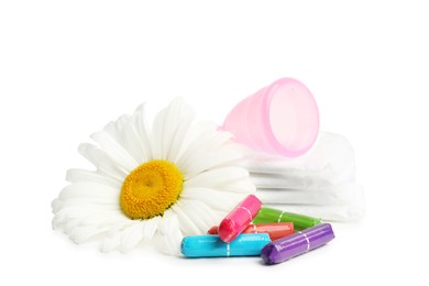 Tampons, pads, menstrual cup and chamomile flower on white background