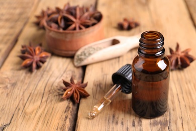 Bottle of essential oil, dropper and anise on wooden table. Space for text