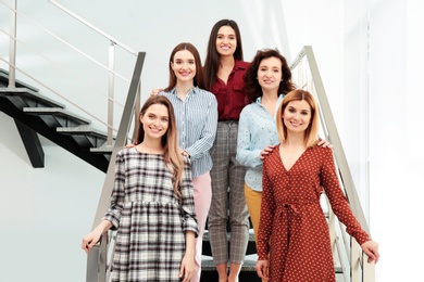 Portrait of happy ladies on stairs indoors. Women power concept
