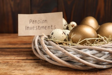 Different eggs and card with phrase Pension Investments in nest on wooden table, closeup