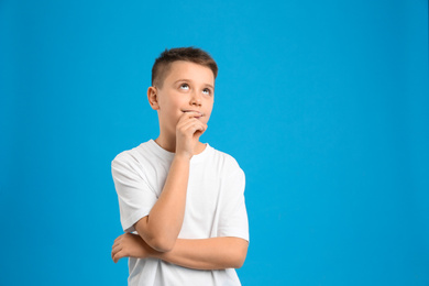 Portrait of preteen boy on light blue background, space for text