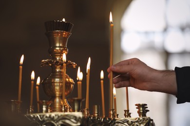 Man putting candle on stand in church, closeup. Baptism ceremony