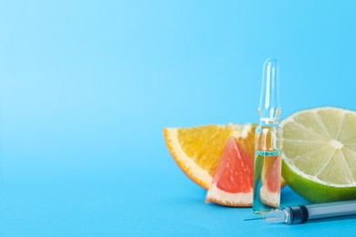 Pharmaceutical ampoule with medication, syringe and citrus fruits on light blue background, closeup. Space for text