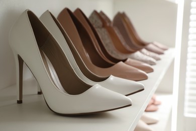 Different stylish women's shoes on shelf in dressing room, closeup