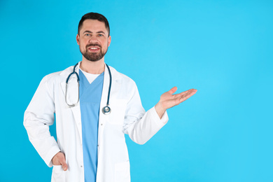 Mature doctor with stethoscope on blue background, space for text