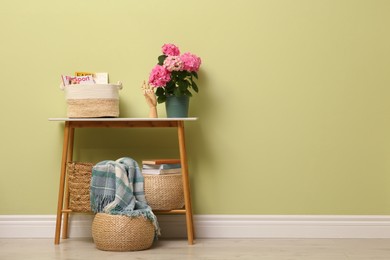 Console table with decor and beautiful hortensia flower near light green wall in hallway, space for text. Interior design