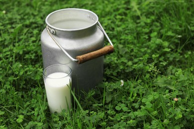 Photo of Can and glass with fresh milk on green grass outdoors