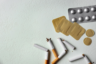 Nicotine patches, pills and broken cigarettes on white background, flat lay. Space for text