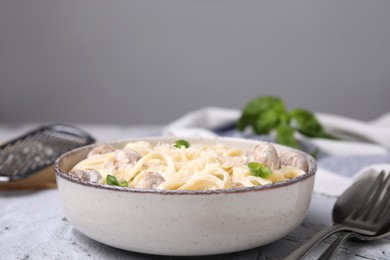 Photo of Delicious pasta with mushrooms and cheese served on light grey textured background, closeup