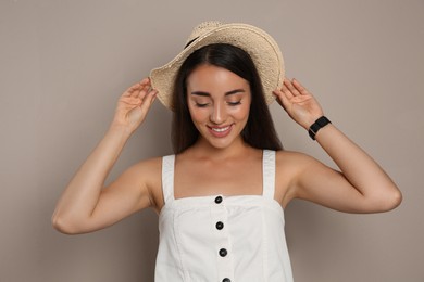 Beautiful young woman wearing straw hat on beige background. Stylish headdress