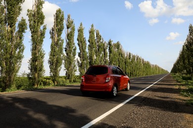 Red car on asphalt road in countryside