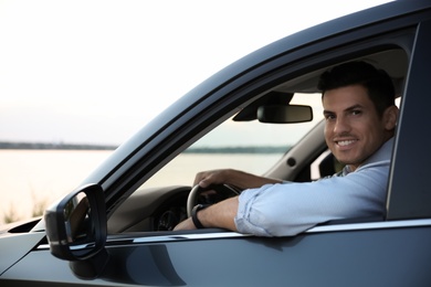 Handsome man in his modern car, view from outside