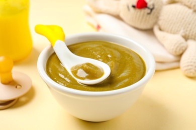 Bowl of healthy baby food on yellow background, closeup