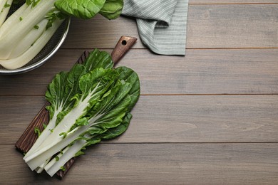 Photo of Fresh green pak choy cabbage with water drops on wooden table, flat lay. Space for text