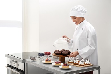 Female chef with pastries at table in kitchen