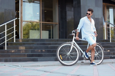 Handsome young hipster man with bicycle outdoors