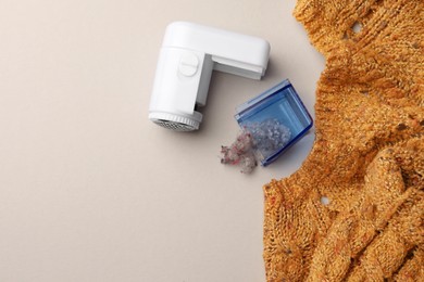 Photo of Modern fabric shaver with fuzz and knitted sweater on white background, flat lay. Space for text