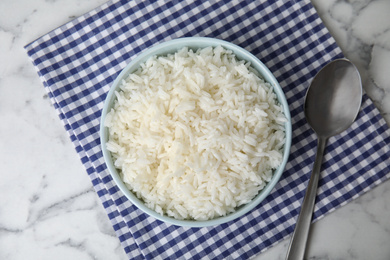 Bowl with tasty cooked rice on marble table, flat lay