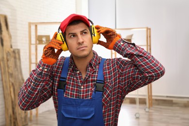 Worker wearing safety headphones indoors. Hearing protection device