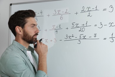Photo of Mature teacher at whiteboard in classroom during math lesson