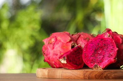 Photo of Delicious cut and whole dragon fruits (pitahaya) on wooden table. Space for text