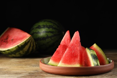 Plate with slices of juicy watermelon on wooden table, space for text