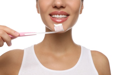 Woman holding toothbrush with paste on white background, closeup